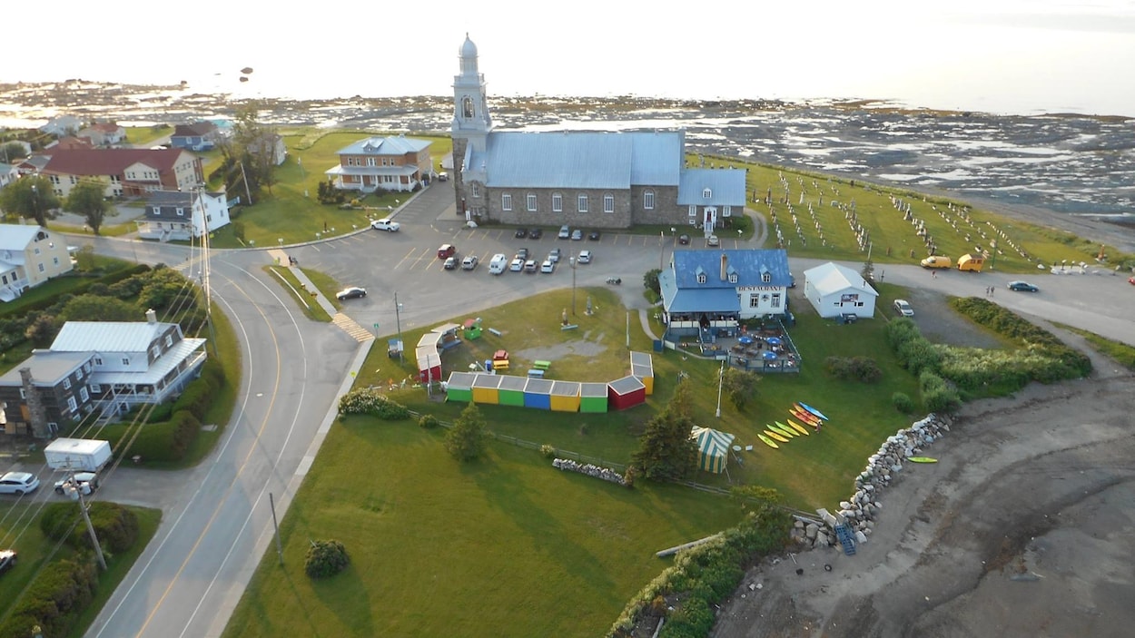 Vue aérienne des cabanes colorées des producteurs, sur un terrain vague à côté de l'église et d'un restaurant de Sainte-Luce.