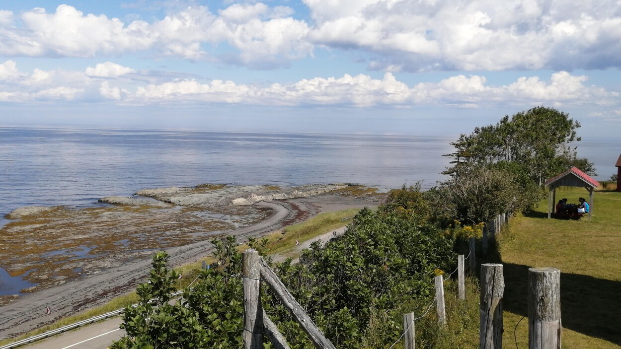 Une colline gazonnée surplombe la route 132, qui borde le fleuve.