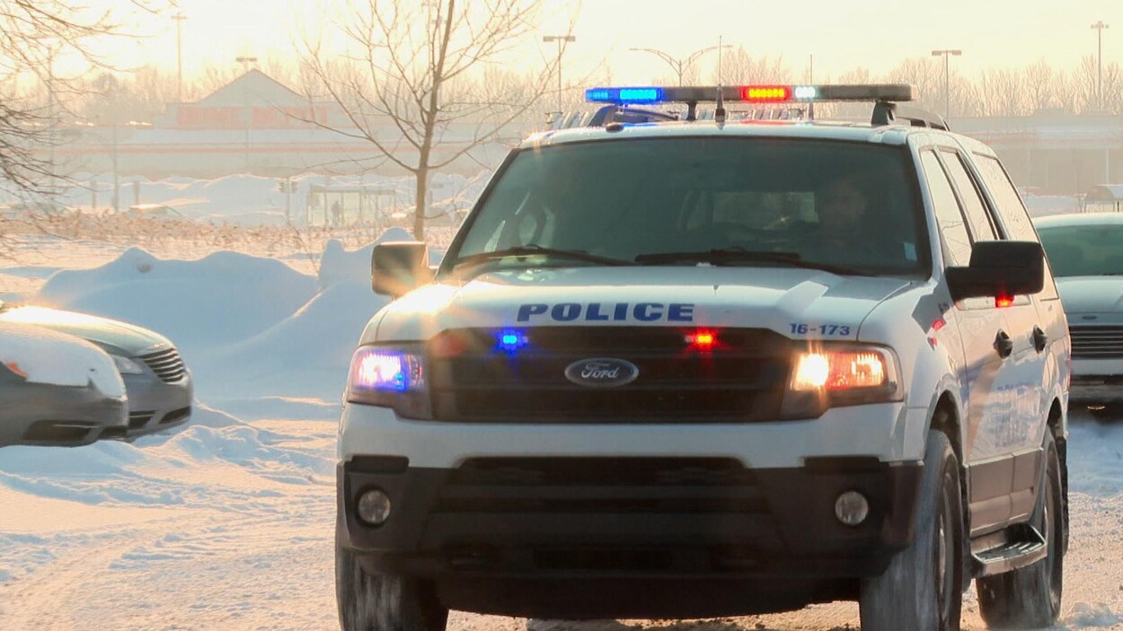 Un VUS de la police de Lévis, dont les gyrophares sont allumés, circule dans un stationnement, en hiver.