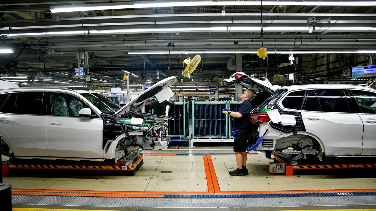 Un homme inspecte un VUS dans une usine.