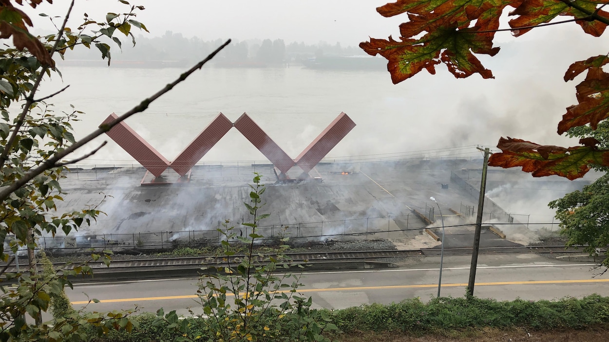 La statue en forme de W entourée de fumée.