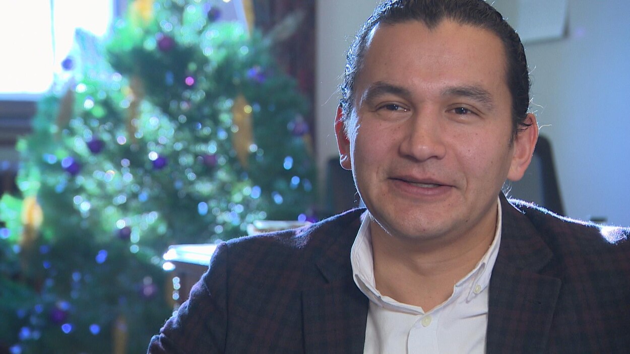 Gros Plan sur Wab Kinew, en entrevue avec Radio-Canada. Au fond derrière lui, on aperçoit un arbre de Noël et le coin de son bureau.