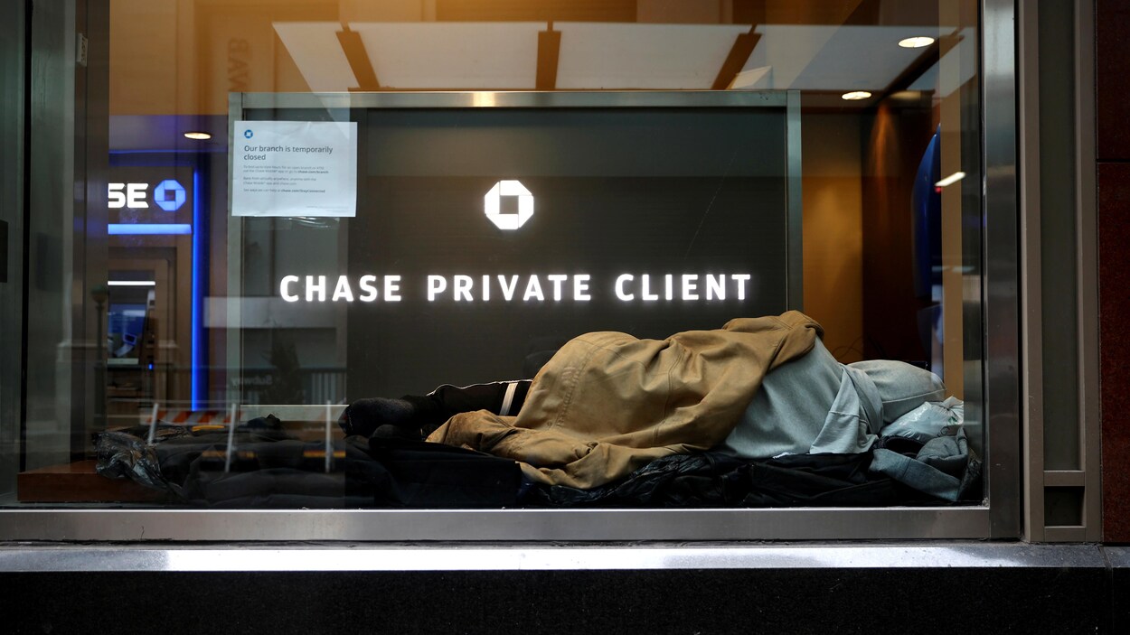 Un sans-abri dort devant la vitrine d'une succursale de la banque Chase.