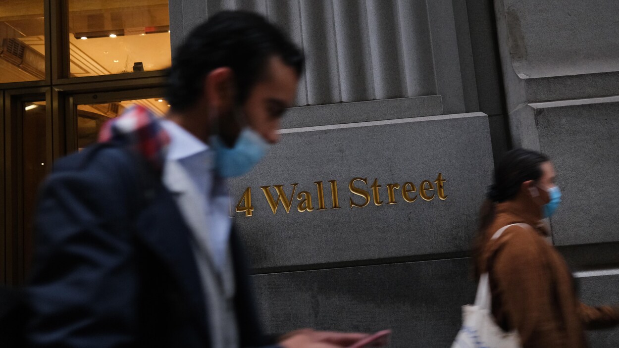 Deux hommes masqué passent devant l'édifice de la Bourse de New York.