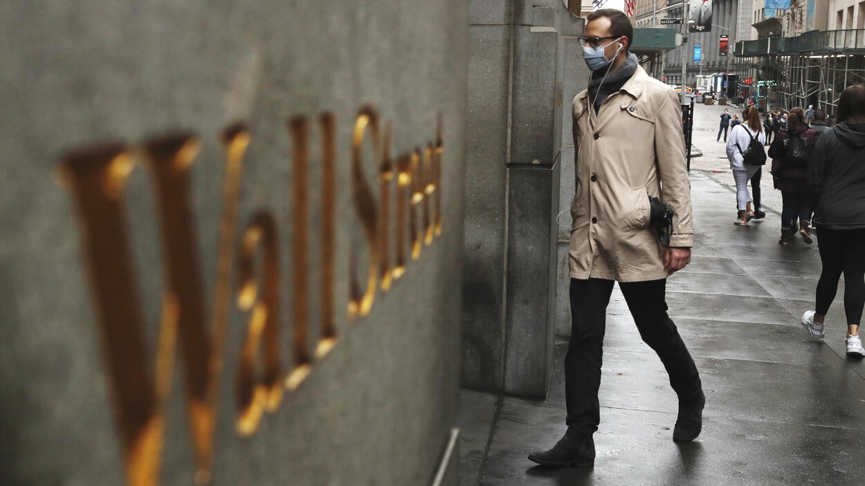 Un homme qui porte un masque de protection médicale entre dans l'édifice de la Bourse de New York.