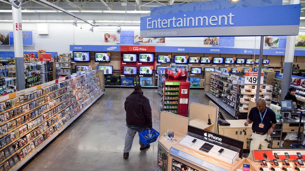 Un homme marche avec un panier dans le département d'électronique d'un magasin Walmart.