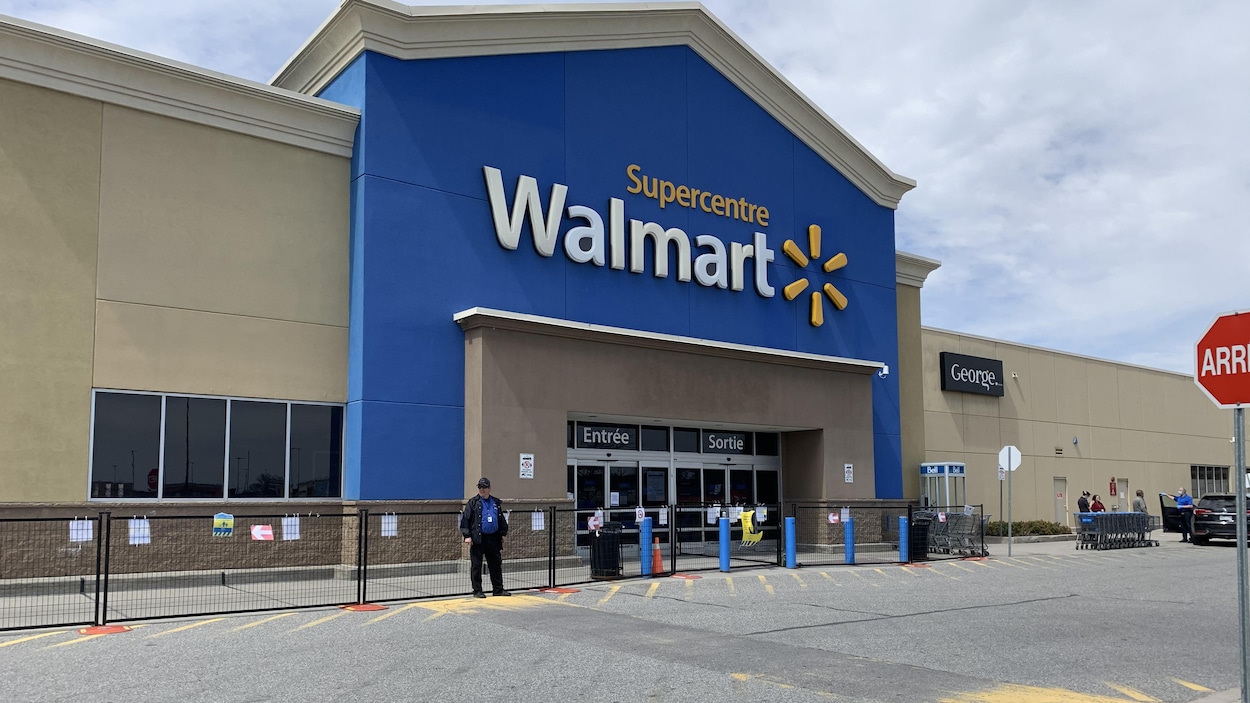 Un agent de sécurité près de la porte du magasin bloquée par une clôture.