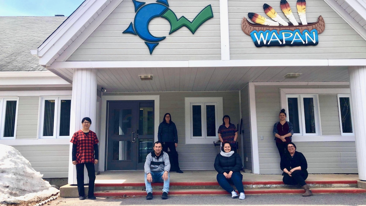 Des gens posent devant l'affiche de Wapan.