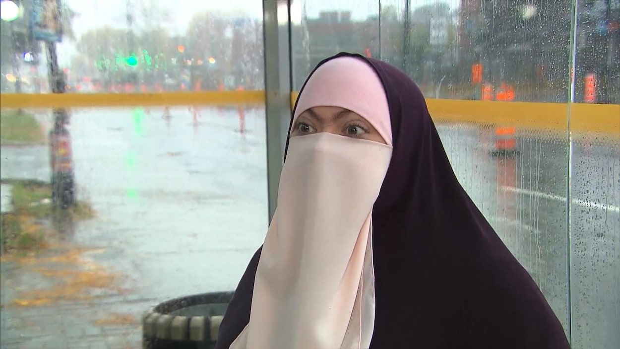 La femme porte le niqab dans un abri d'autobus.