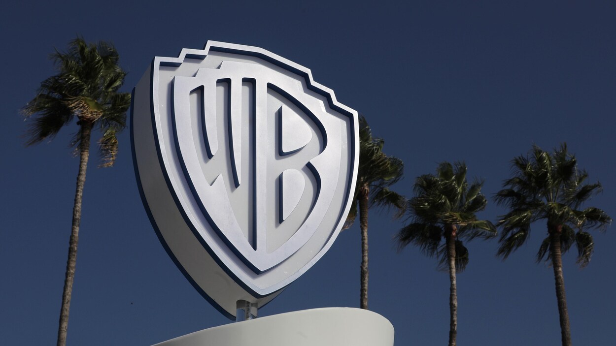 Le logo de Warner Bros est photographié à l'extérieur devant des palmiers.