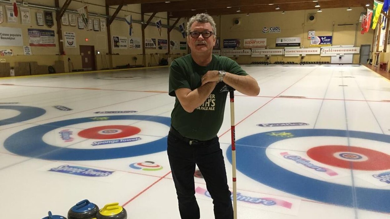 Gary Walsh debout sur une patinoire s'appuie sur son balais de curling