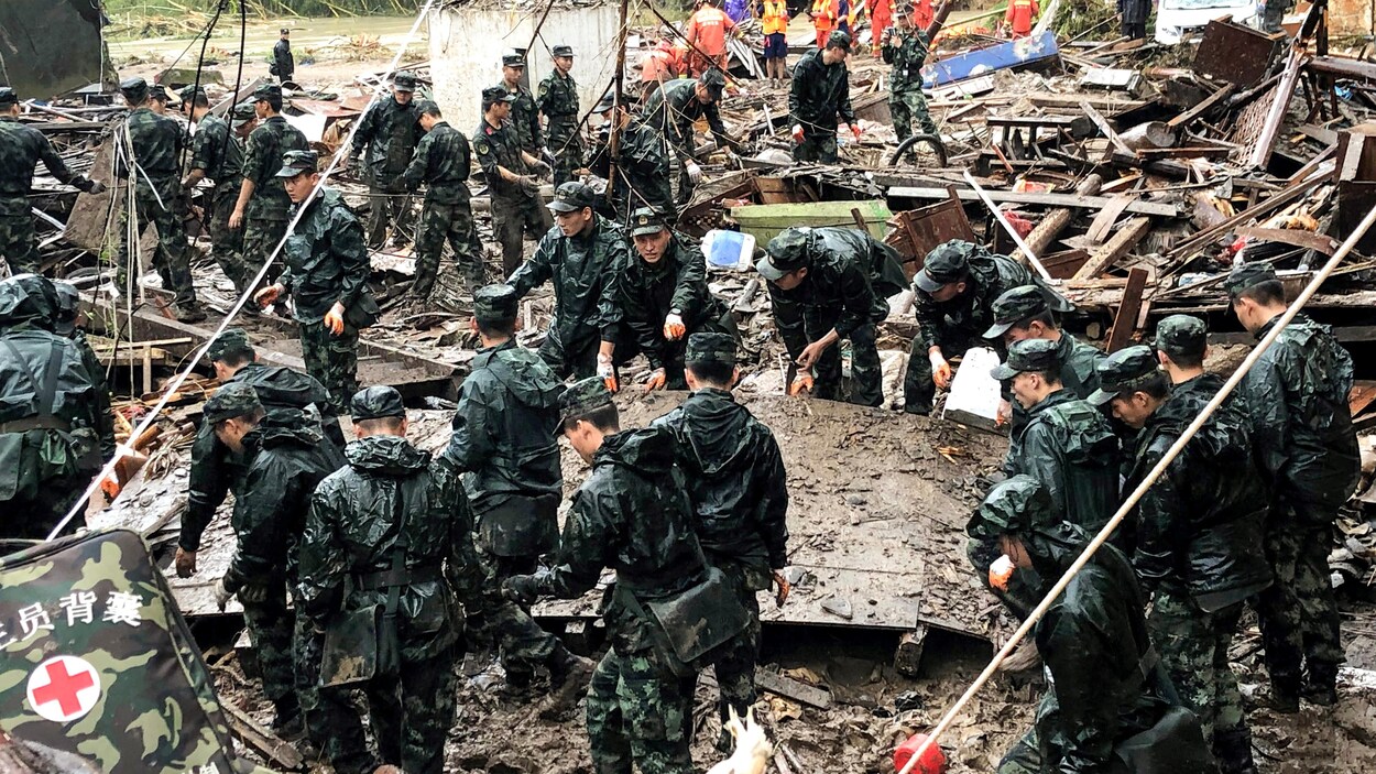 Des sauveteurs et des policiers paramilitaires fouillent les décombres de bâtiments endommagés par les pluies torrentielles causées par le typhon Lekima, à Yongjia, à Wenzhou, dans la province chinoise du Zhejiang, le 11 août 2019.