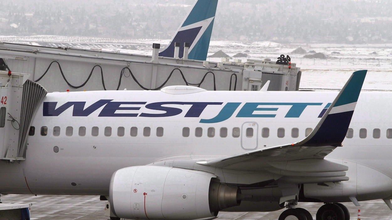 Gros plan d'un avion blanc sur lequel est écrit en lettres bleues Westjet.