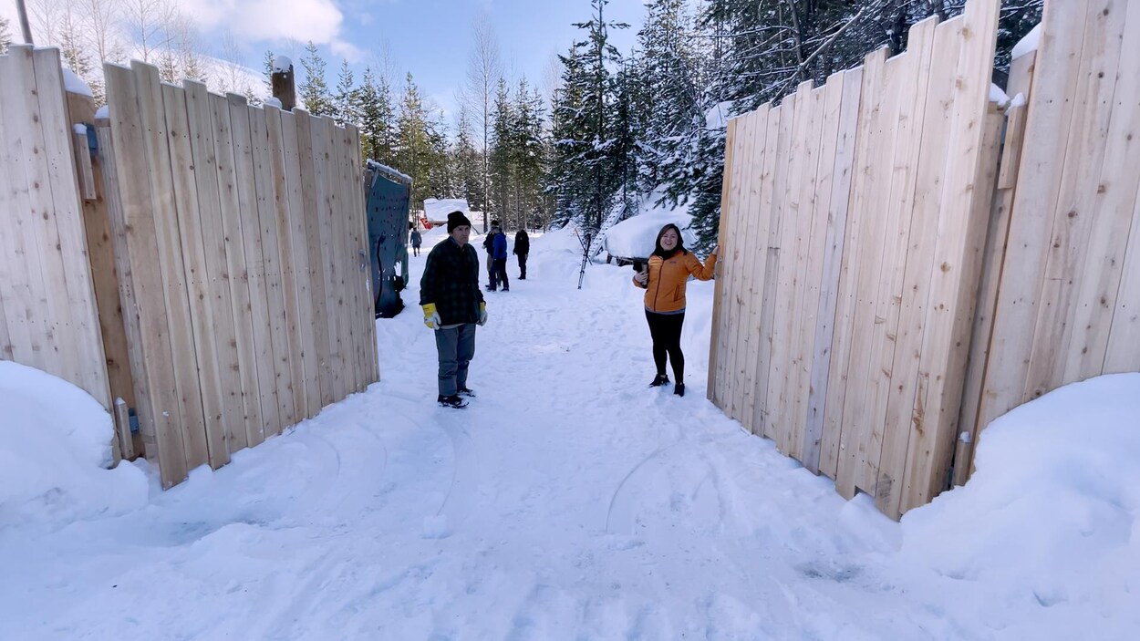 Une femme devant un portail de bois.
