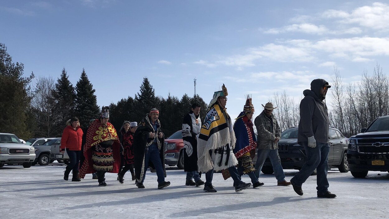Des Autochtones en tenue traditionnelle marchant dans un stationnement