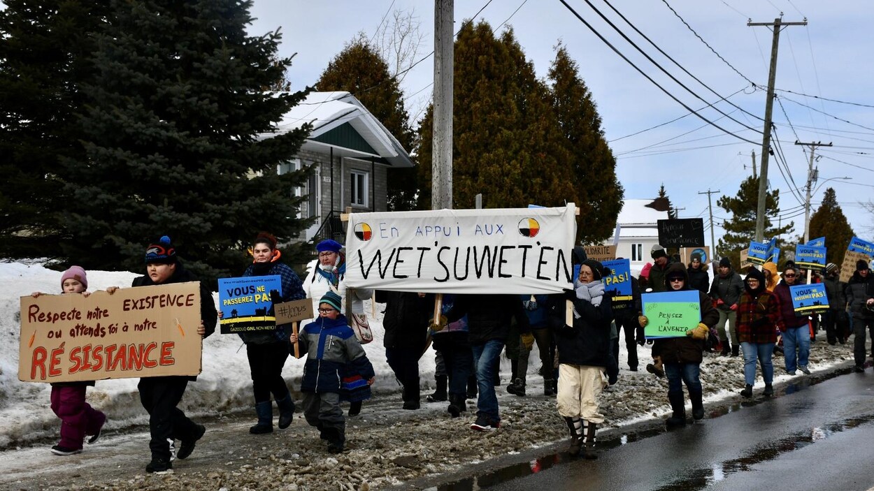 Des manifestants marchent avec des affiches.