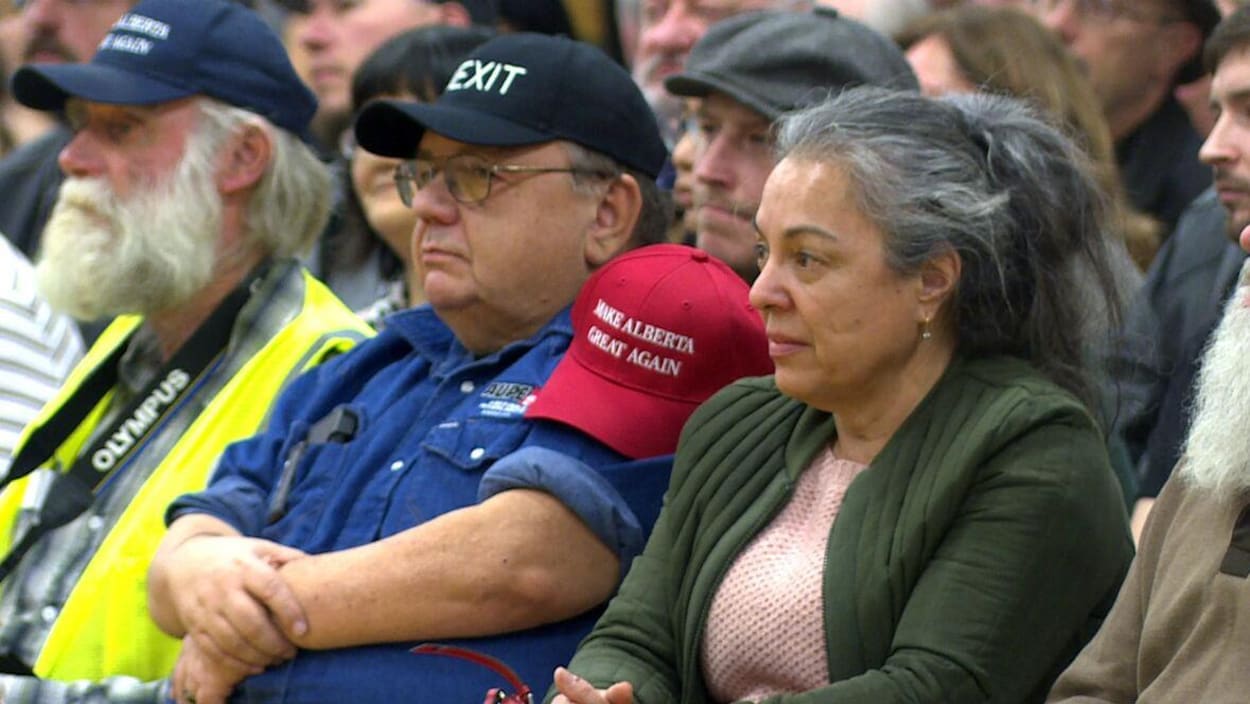 Des personnes assises avec des casquettes Make Alberta Great Again et Wexit dans une école de Calgary pendant un rassemblement du mouvement Wexit.