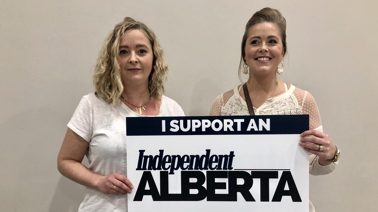 Deux femmes tiennent une pancarte où l'on peut lire le message : "J'appuie une Alberta indépendante."