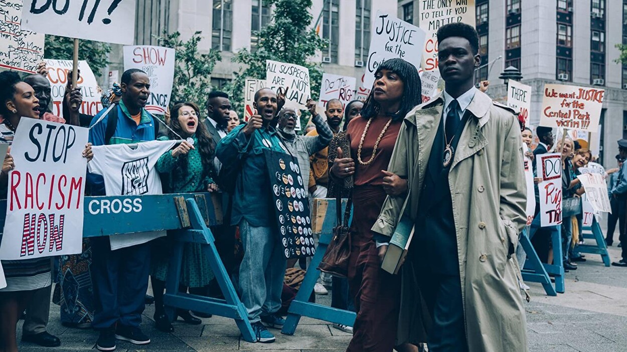 Une femme noire et un jeune homme noir avance au milieu de personnes qui manifestent.