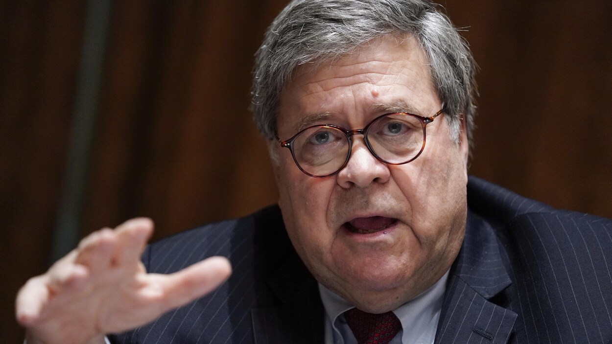 William Barr parle en tendant une main devant lui.