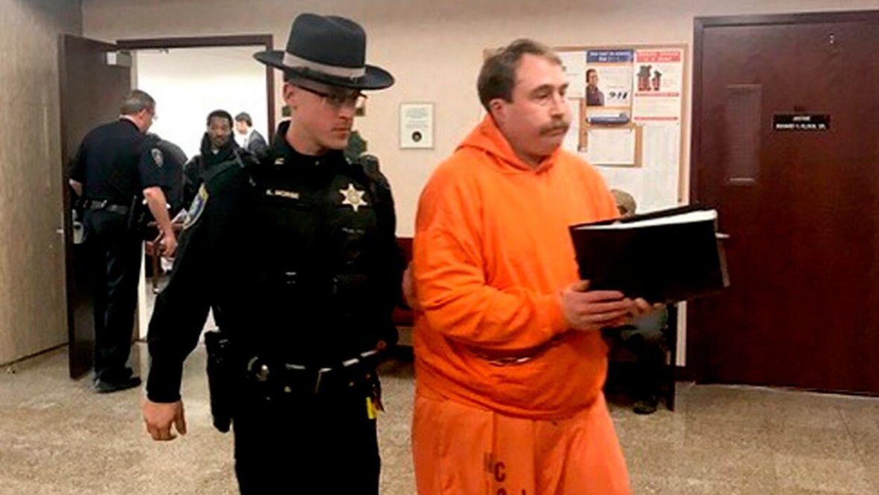 William Shrubsall marche dans un couloir du palais de justice escorté par un shérif américain.