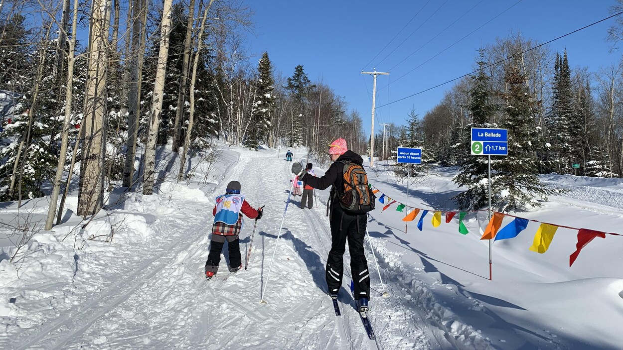 Une femme et 4 enfants sur une piste de ski de fond.