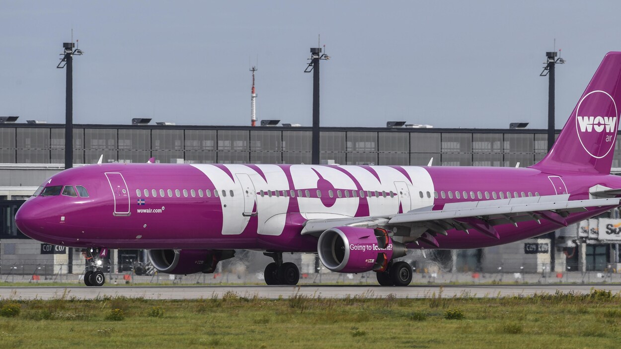 Photo d'un avion mauve au sol sur lequel est écrit « WOW »