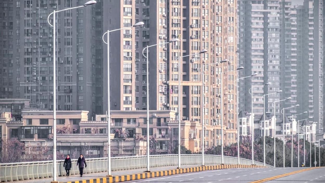 Des personnes portant un masque marchent dans les rues désertes de Wuhan.