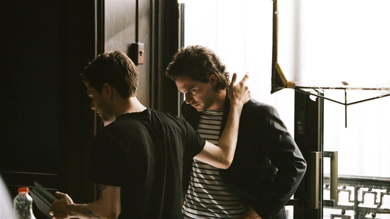 Xavier Dolan tient Kit Harington par l'épaule tout en lisant quelque chose sur le plateau de «The Death and Life of John F. Donovan».