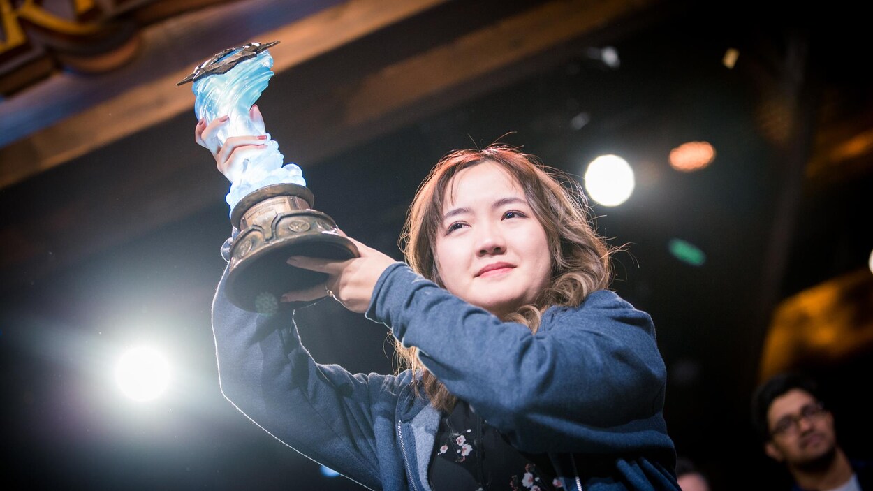 Une femme tient un trophée après avoir remporté une compétition au BlizzCon 2019.