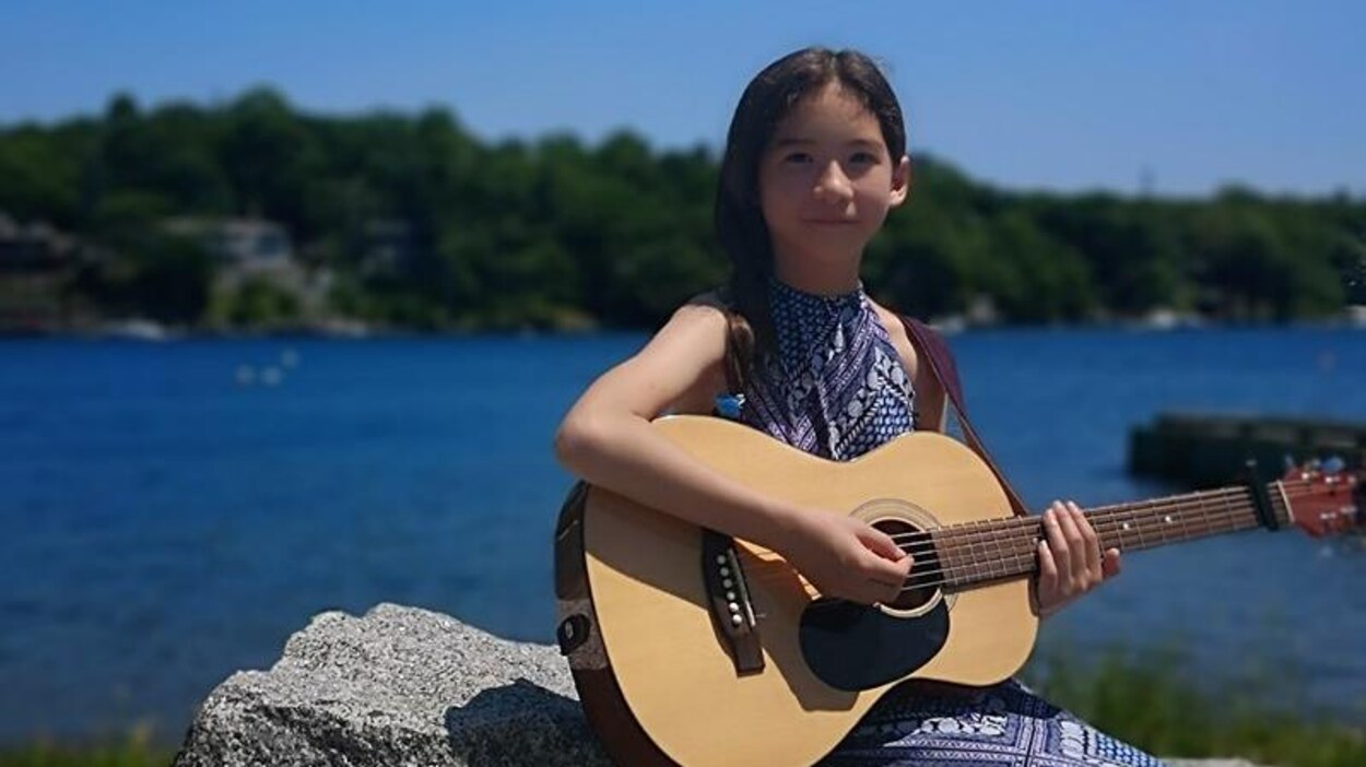 Xuan Trzebiatowski avec sa guitare, sur le bord de l'eau