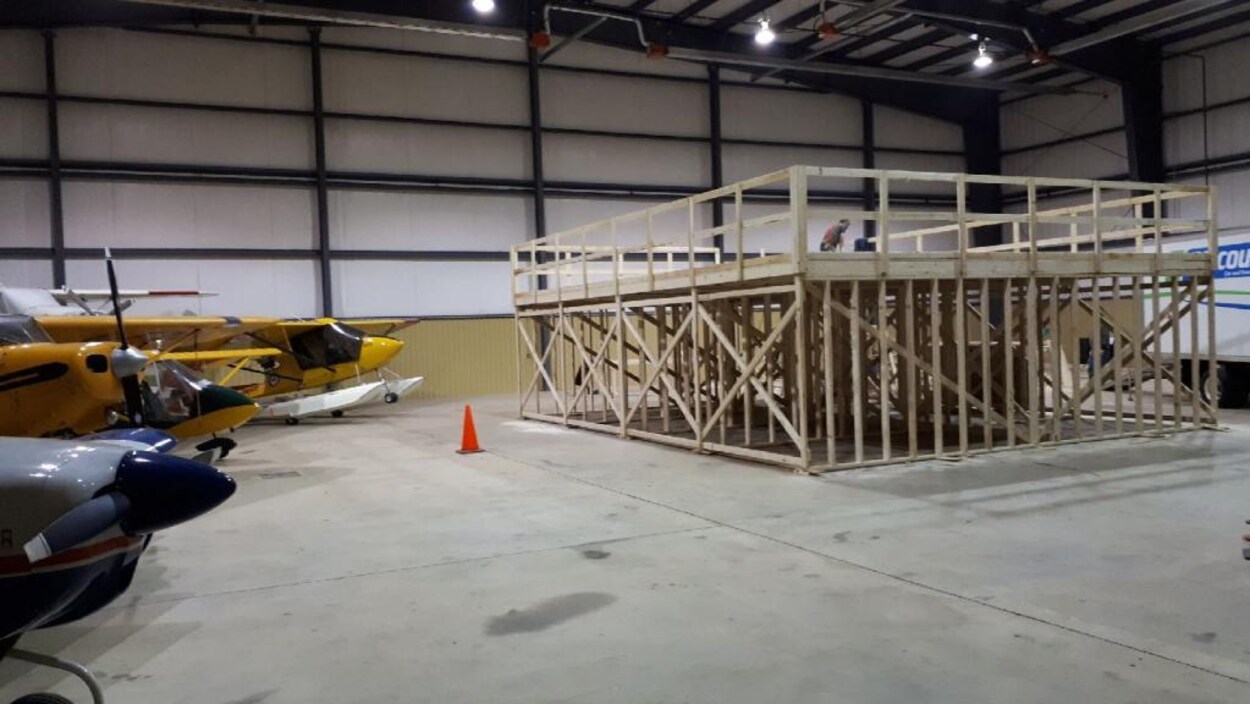 Des travailleurs construisent une plate-forme en bois dans le hangar Des travailleurs construisent une plate-forme en bois dans le hangar