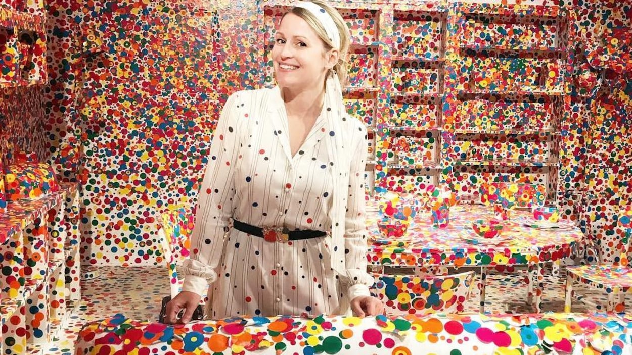 La jeune femme pose dans une robe à pois de couleurs différentes dans une exposition avec des pois sur fond blanc.