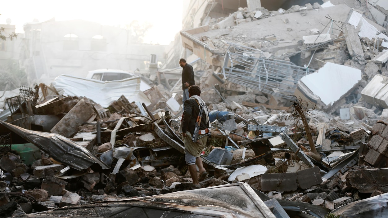 À Sanaa, au Yémen, des personnes marchent dans les débris à la suite d'un raid aérien. À Sanaa, au Yémen, des personnes marchent dans les débris à la suite d'un raid aérien.