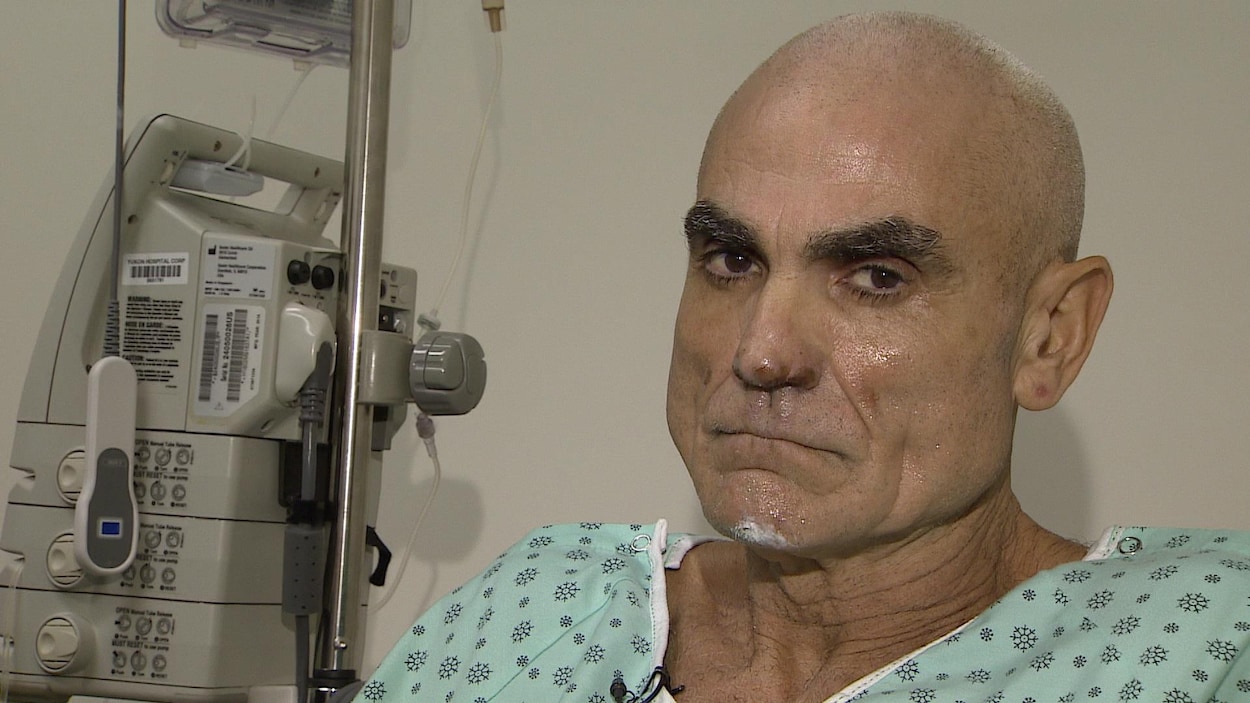 Gros plan de la tête et des épaules d'un homme en habit d'hôpital.
