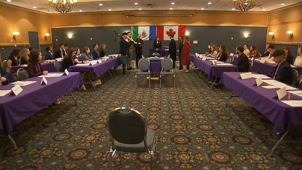 Des gens dans une salle de conférence écoutent un discours.