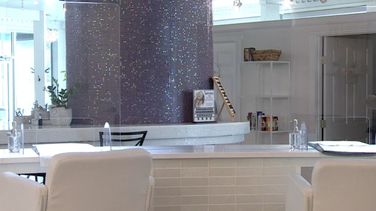 Des panneaux transparents installés entre les chaises des clients dans un salon de coiffure.