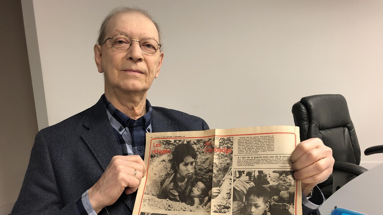 Yvan Laniel pose pour la caméra en tenant un journal.