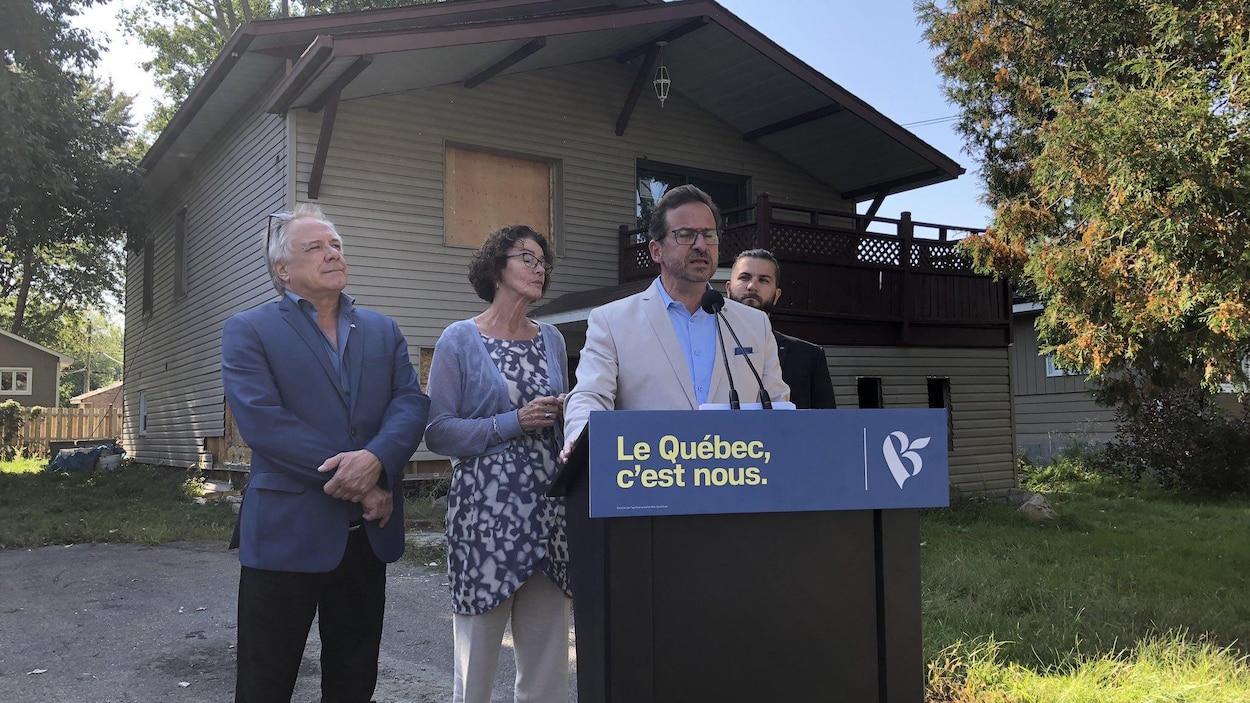 Yves-François Blanchet fait une annonce devant une maison endommagée par un sinistre.
