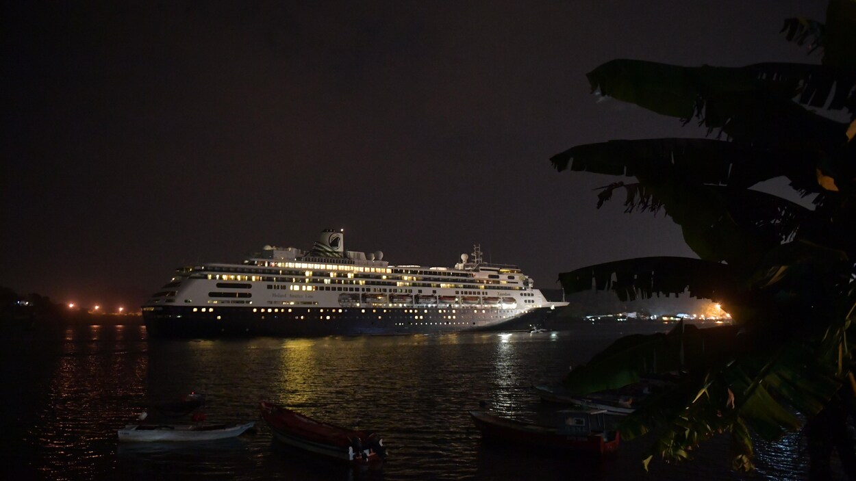 Le paquebot Zaandam illuminé flotte dans le canal de Panama en pleine nuit.