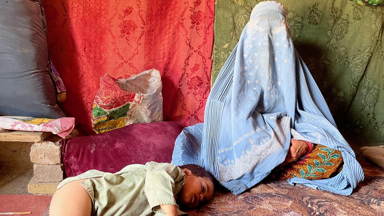 Un enfant est couché près d'une femme qui porte une burqa bleue.