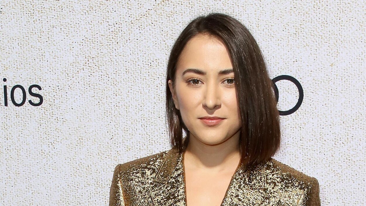 La femme prend la pose pour une photo sur le tapis rouge d'un événement mondain.