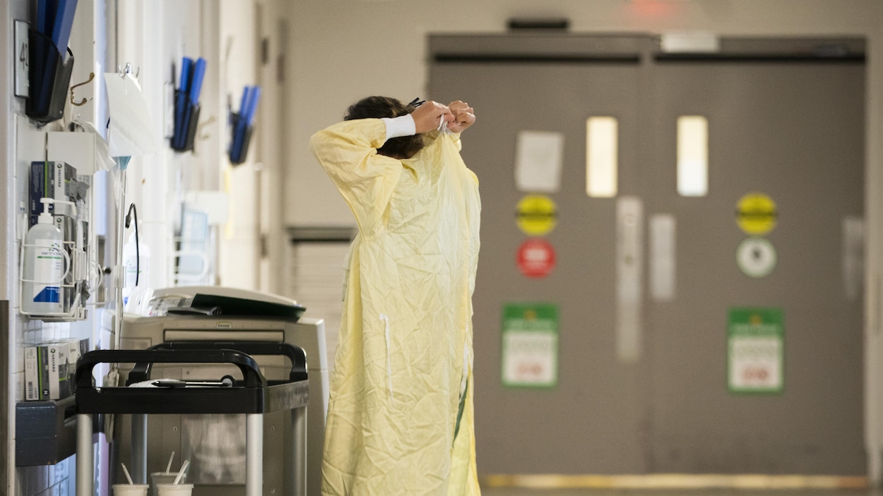Une femme noue une blouse médicale.