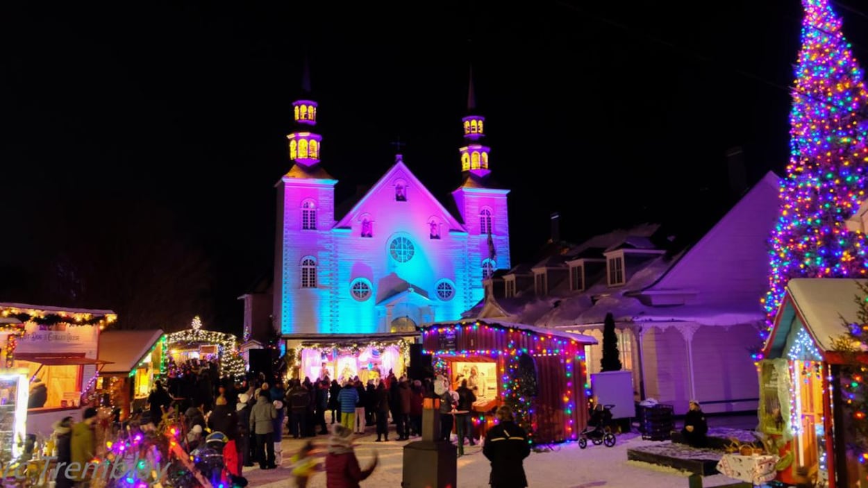 Marché de Noël avec sapin de noël , église et cabanes de bois illuminés.