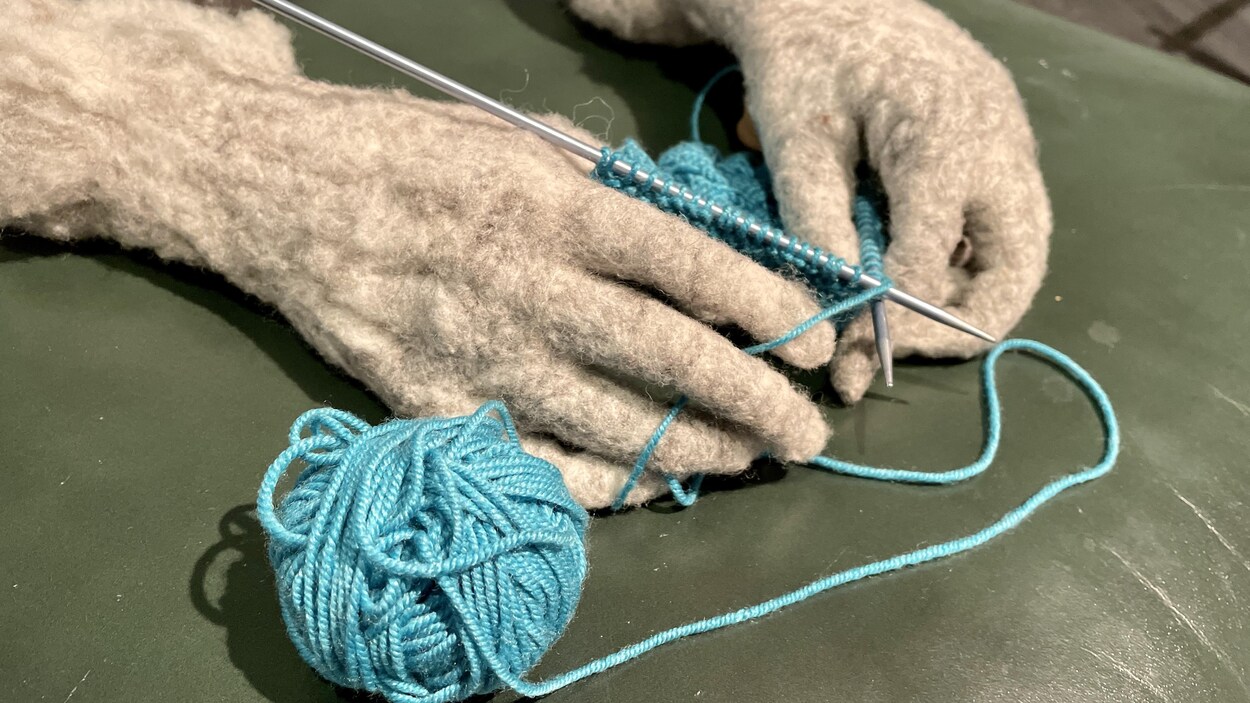 Mains de laine qui tricotent à partir d'une pelote de laine. 