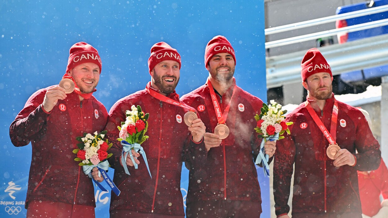 Justin Kripps, Ryan Sommer, Cam Stones et Benjamin Coakwell sourient, médaille de bronze au cou.