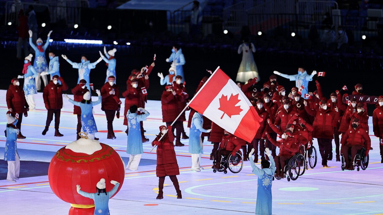 La délégation canadienne paralympique entrent dans le stade lors de la cérémonie d'ouverture des Jeux de Beijing 2022. Ina Forrest brandit le drapeau canadien.