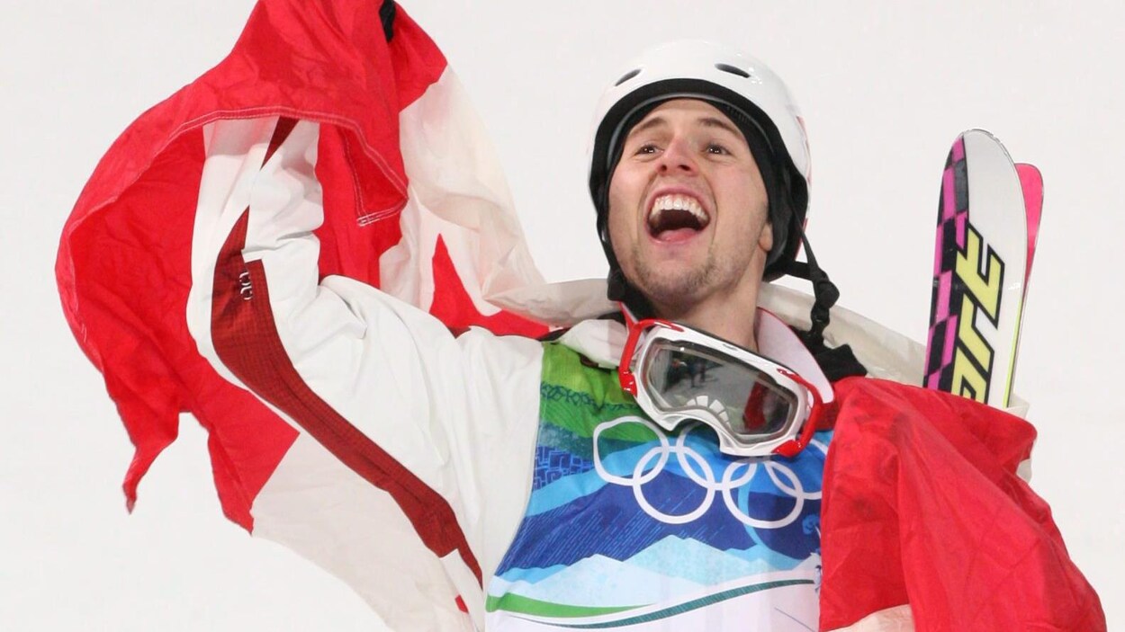 Drapé du drapeau canadien, il lève le bras en l'air.