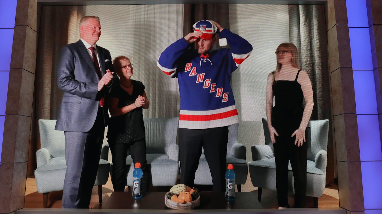 Alexis Lafrenière place une casquette sur sa tête.