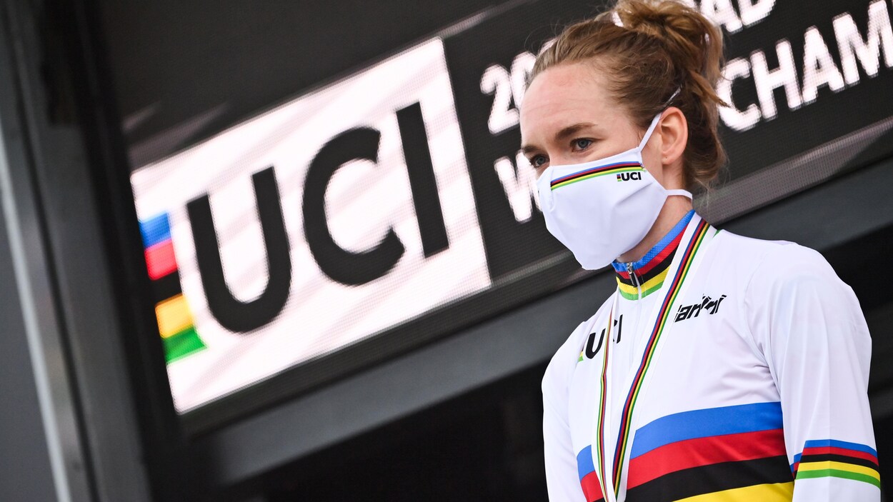 Une cycliste portant un masque se tient debout sur un podium.